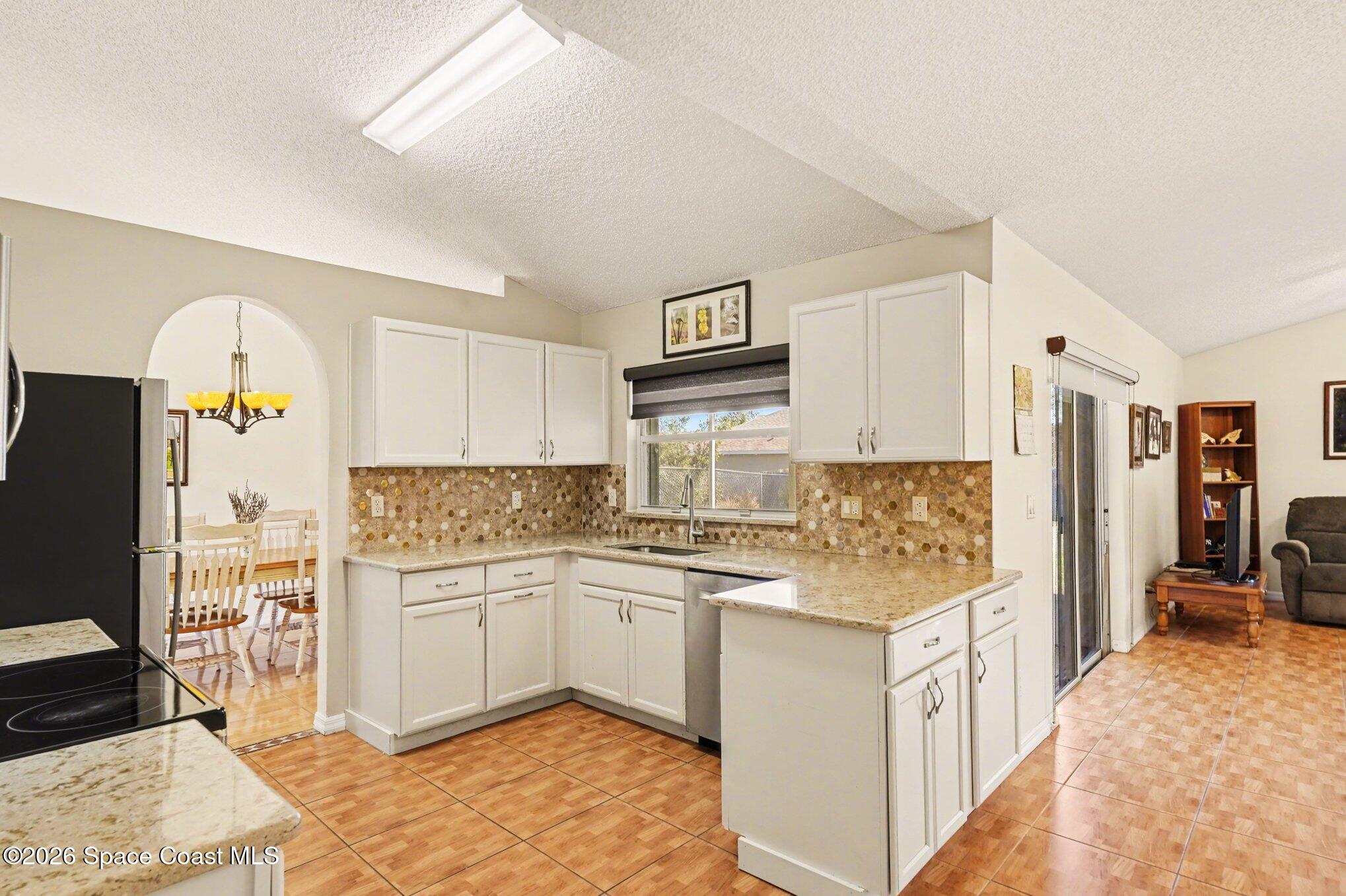 938 Commerce Road Southeast Palm Bay, FL 32909 - Photo 11 of 31 a kitchen with stainless steel appliances granite countertop a sink stove and refrigerator