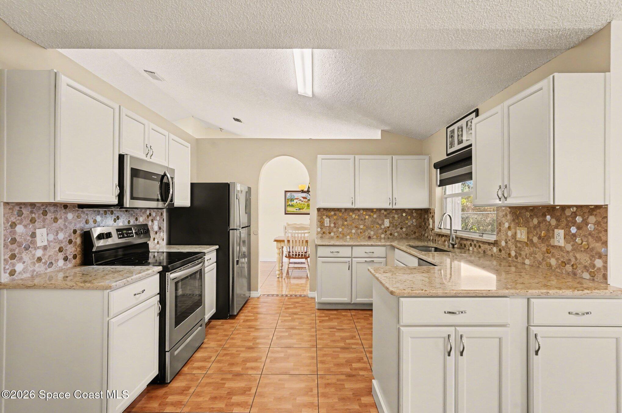 938 Commerce Road Southeast Palm Bay, FL 32909 - Photo 14 of 31 a kitchen with cabinets stainless steel appliances and a sink