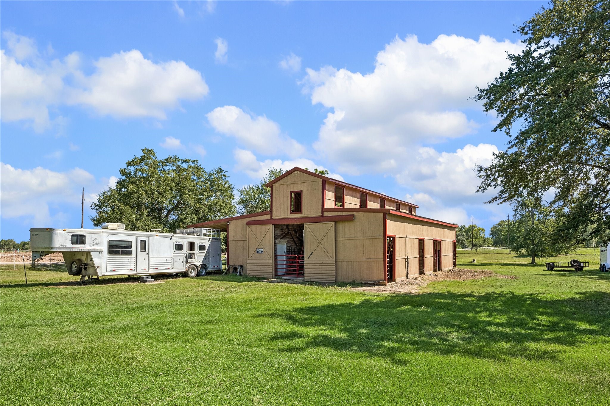 4530 Pool Hill Road Brookshire, TX 77423 - Photo 41 of 46 Expansive property featuring a spacious barn with ample storage, surrounded by lush greenery and mature trees, perfect for equestrian enthusiasts.