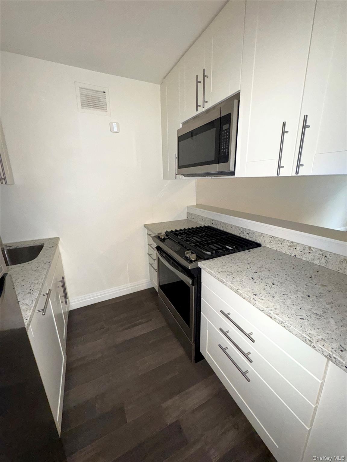 280 Rector Place, Unit 1G Manhattan, NY 10280 - Photo 5 of 17 a kitchen with granite countertop a stove and a microwave