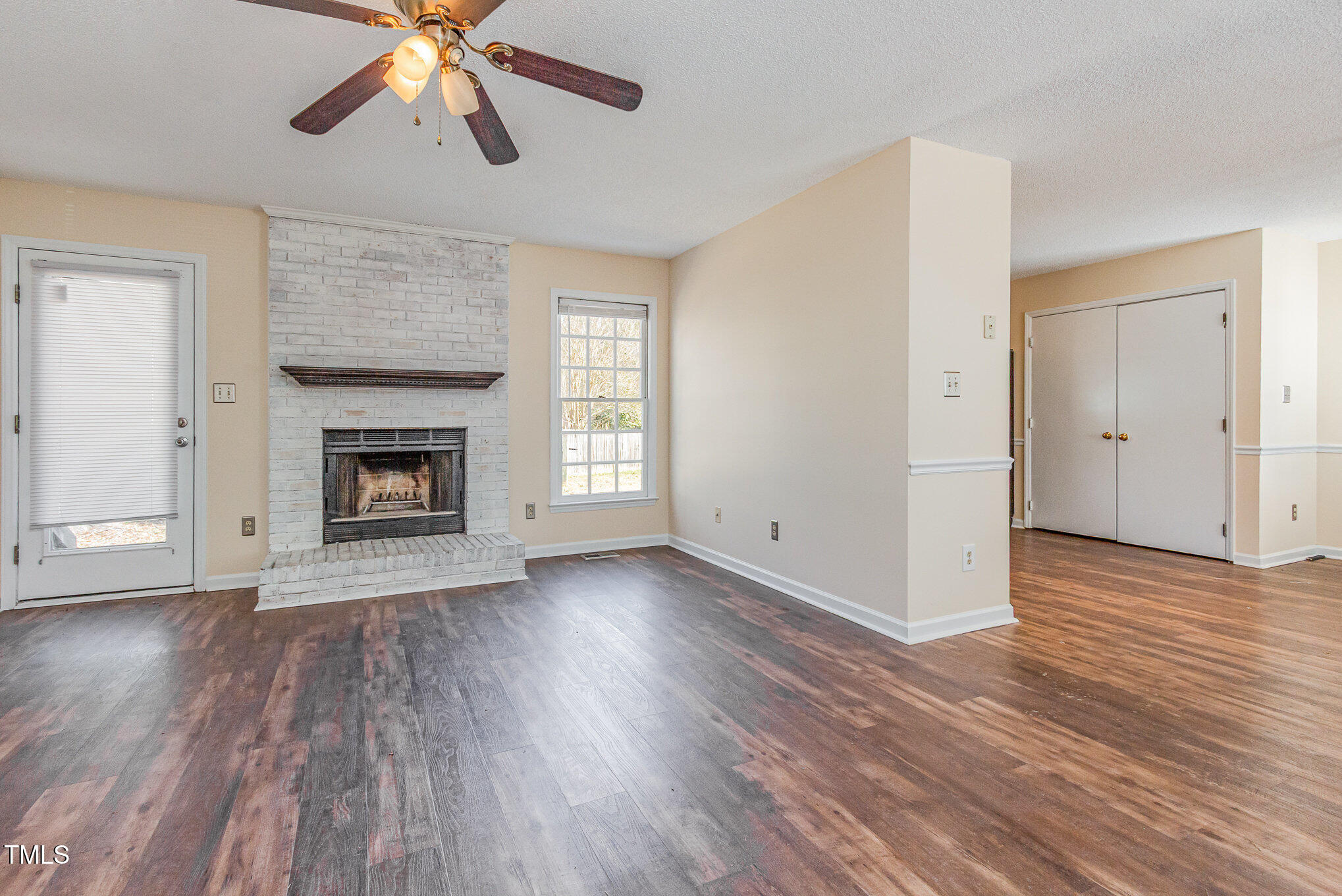 3332 Castlegate Drive Raleigh, NC 27616 - Photo 7 of 22 an empty room with wooden floor a ceiling fan a fireplace and windows
