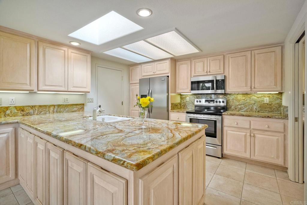 4760 Galicia Way Oceanside, CA 92056 - Photo 14 of 56 a kitchen with kitchen island granite countertop a sink window and cabinets