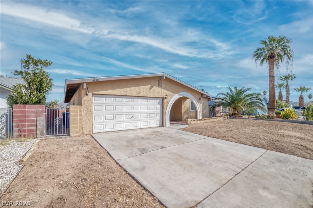 3556 Ruth Drive Las Vegas, NV 89121 - Photo 4 of 21 A modest stucco home with an arched entry and attached garage, nestled among palm trees.