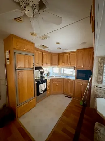 a kitchen with stainless steel appliances granite countertop a refrigerator a sink dishwasher a stove and a refrigerator with wooden floor