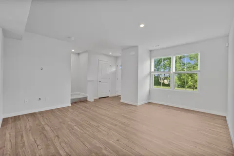 a view of an empty room with wooden floor and windows