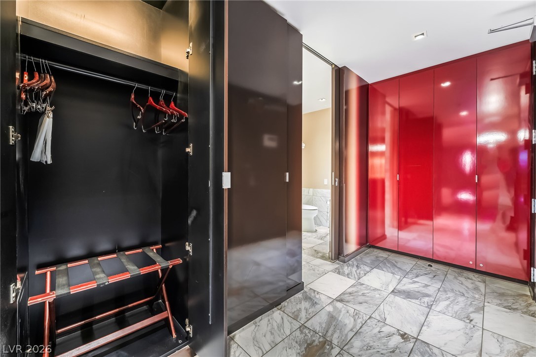 4381 West Flamingo Road, Unit 18305 Las Vegas, NV 89103 - Photo 4 of 19 Marble tile flooring grounds this functional closet space, leading to a glimpse of an adjoining bathroom.