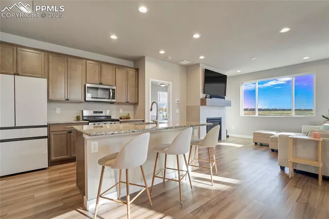 a kitchen with stainless steel appliances granite countertop a stove top oven a sink a refrigerator with white cabinets and wooden floor