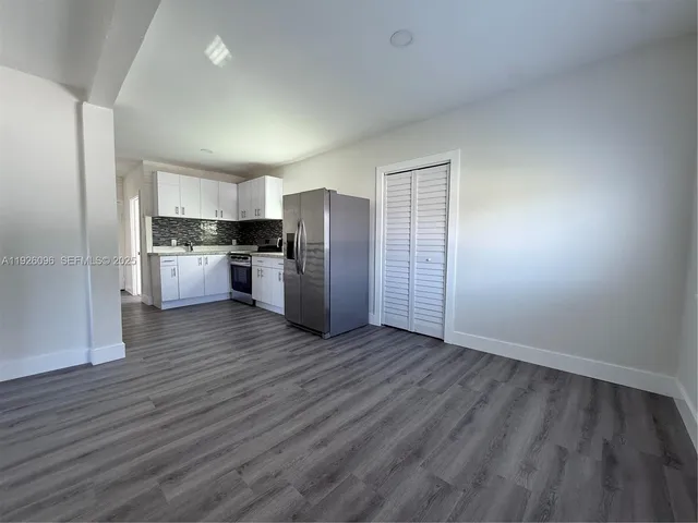 a view of a kitchen with a refrigerator a stove top oven and cabinets