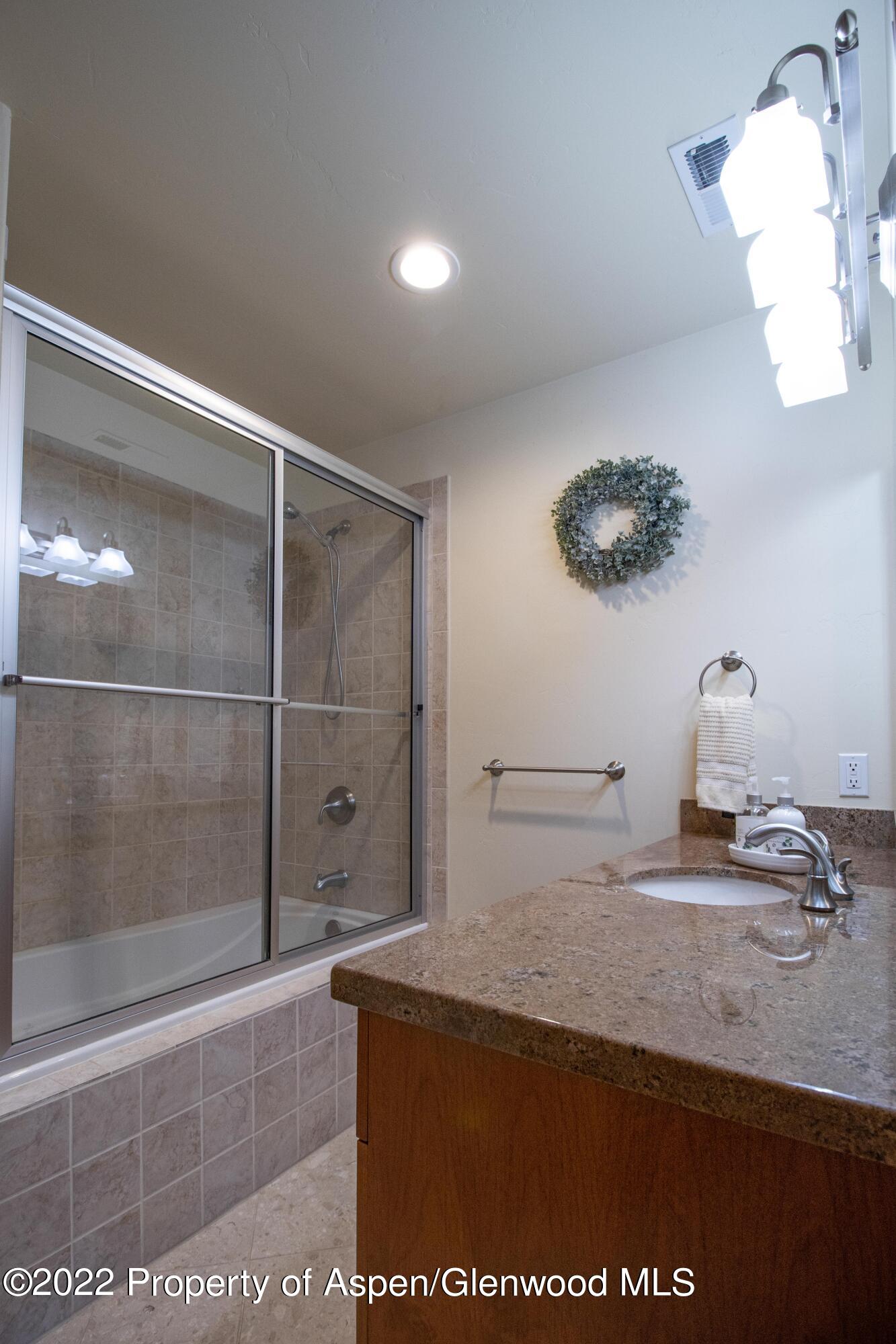 323 Faas Ranch Road New Castle, CO 81647 - Photo 20 of 22 a bathroom with a granite countertop sink a mirror and shower