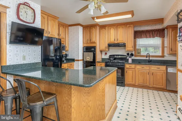 a kitchen with stainless steel appliances granite countertop a stove a sink a microwave and wooden cabinets