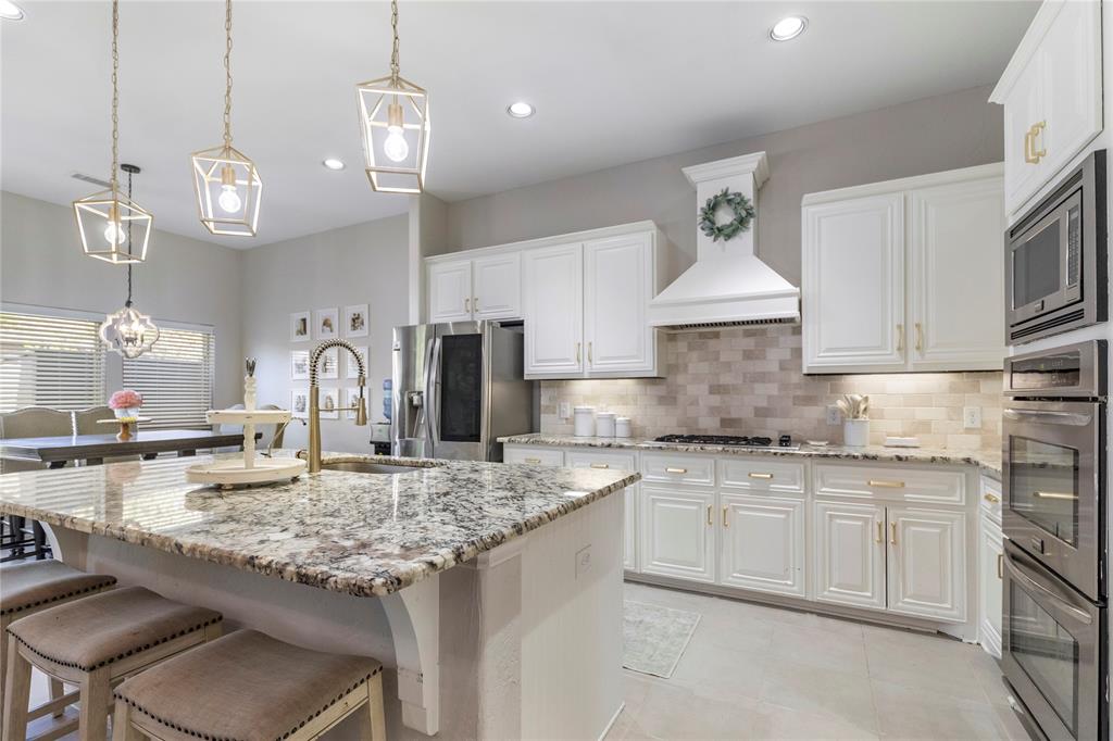 11604 Compton Trail Fort Worth, TX 76244 - Photo 2 of 40 a kitchen with kitchen island granite countertop a sink a center island a stove cabinets and living room view