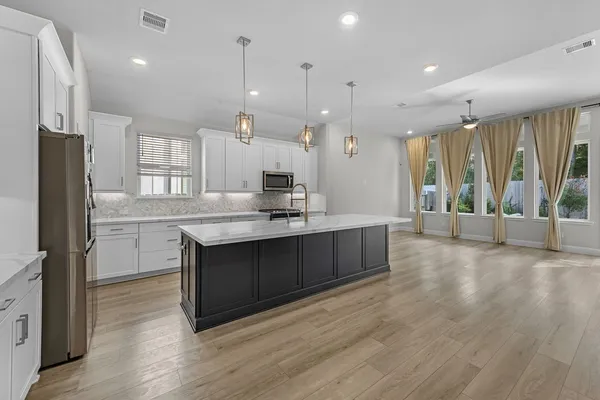 a large kitchen with a large counter top a sink stainless steel appliances and cabinets