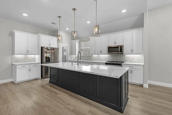 a large kitchen with stainless steel appliances kitchen island granite countertop a sink a counter space and cabinets