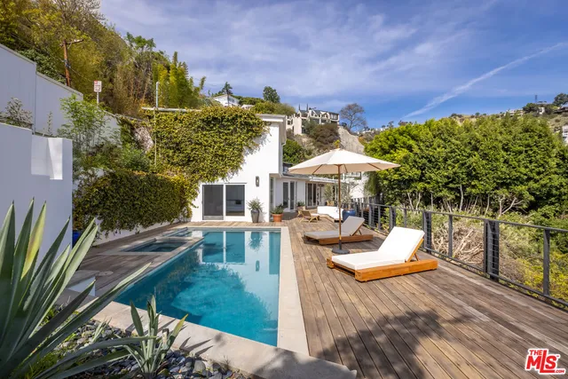 a view of a patio with couches table and chairs with wooden fence and plants