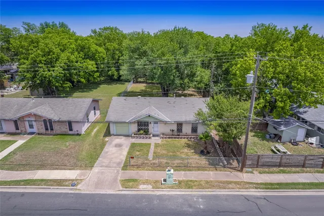 an aerial view of residential houses with outdoor space and trees