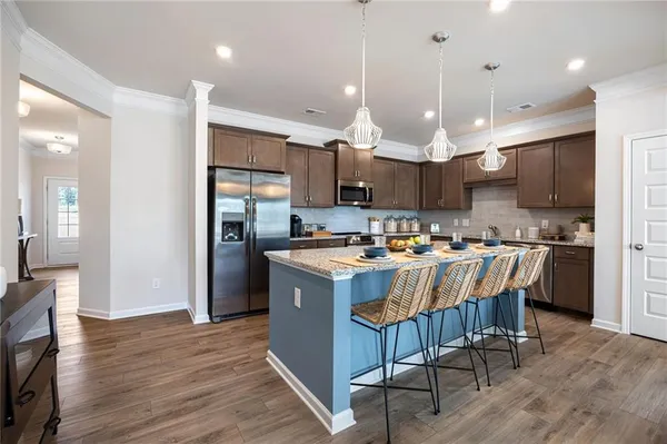 a large kitchen with kitchen island a island a stove a refrigerator a sink dishwasher a oven with a dining table and chairs