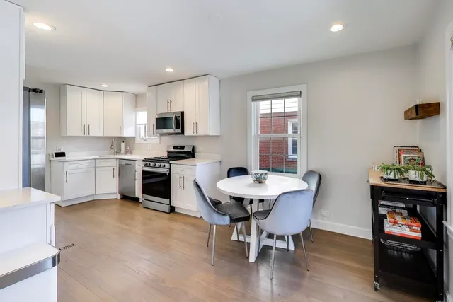 a kitchen with stainless steel appliances a table and chairs in it