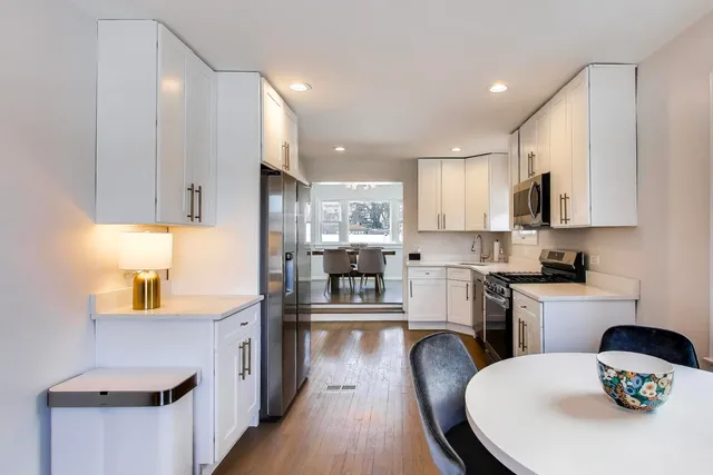 a kitchen with granite countertop white cabinets and stainless steel appliances