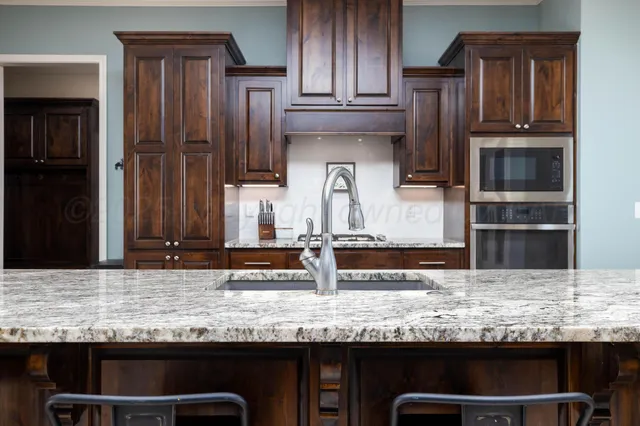 a kitchen with stainless steel appliances granite countertop a kitchen island hardwood floor sink dining table and chairs