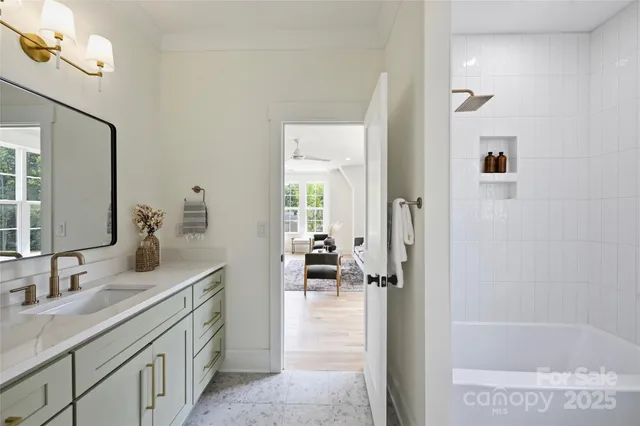 a en suite bathroom with a granite countertop sink a mirror a vanity and a bathtub
