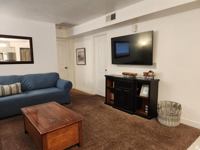 860 South Village Road, Unit H1 St. George, UT 84770 - Photo 3 of 20 Carpeted living area with baseboards and a textured ceiling