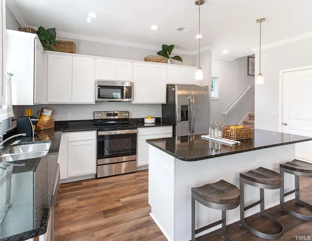 a kitchen with lots of counter space a sink appliances and a living room view