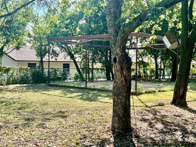 a view of swimming pool with large trees and wooden fence