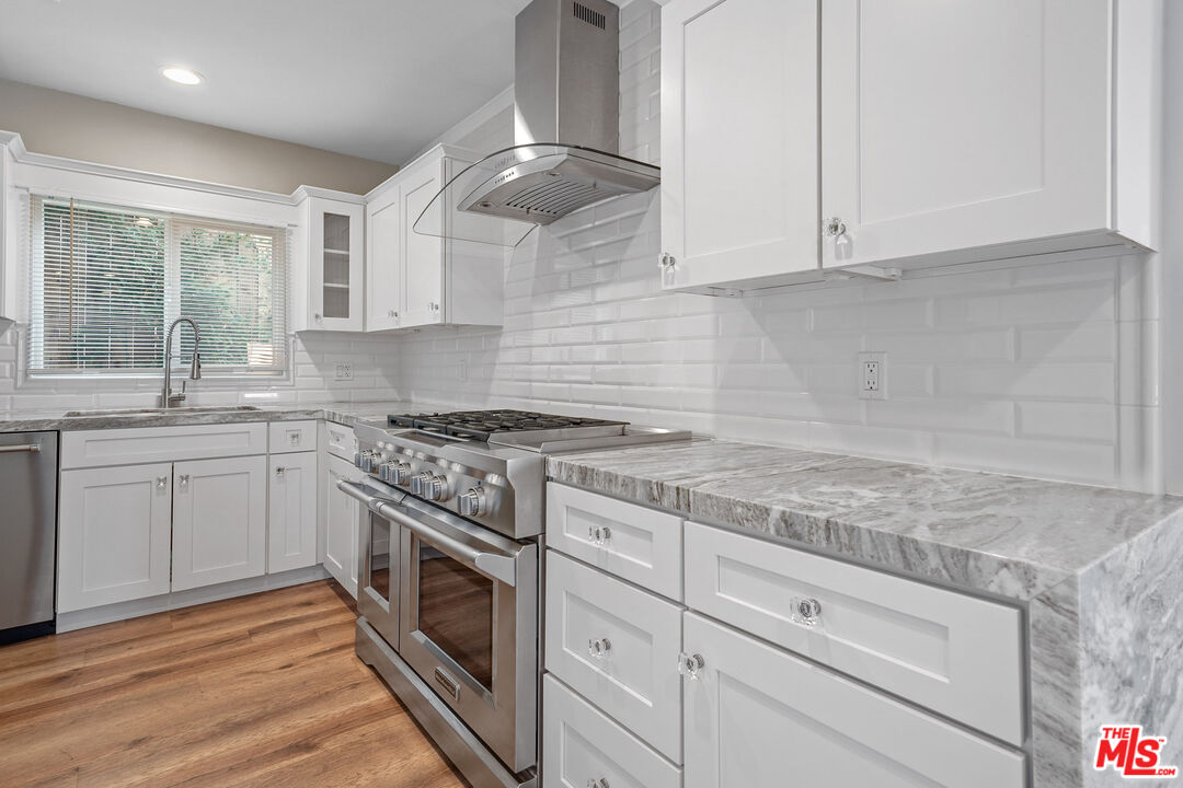 54 West Glenarm Street Pasadena, CA 91105 - Photo 8 of 18 a kitchen with granite countertop stainless steel appliances white cabinets granite counter tops and a wooden floors
