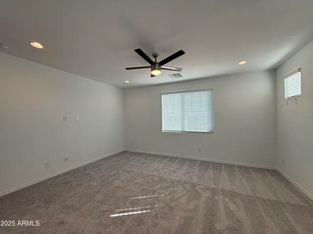 an empty room with windows and ceiling fan