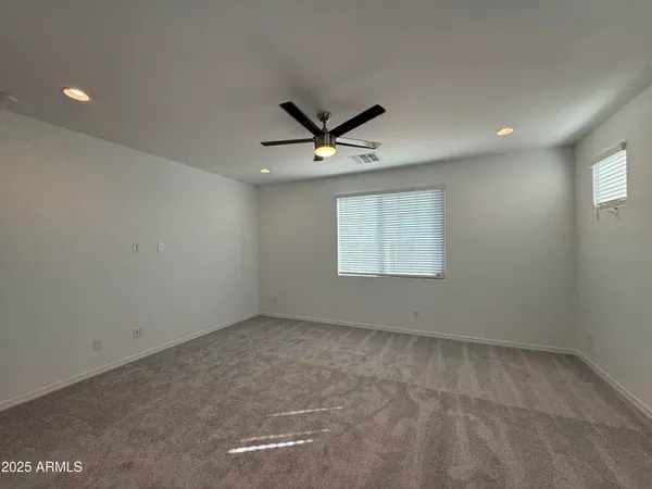 an empty room with windows and ceiling fan