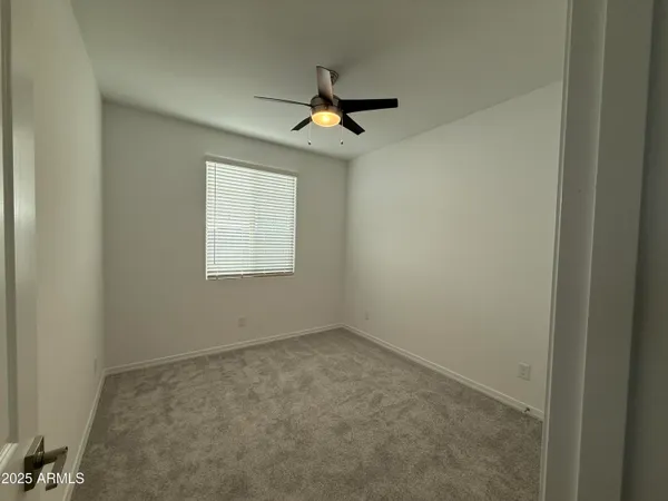 an empty room with windows and fan