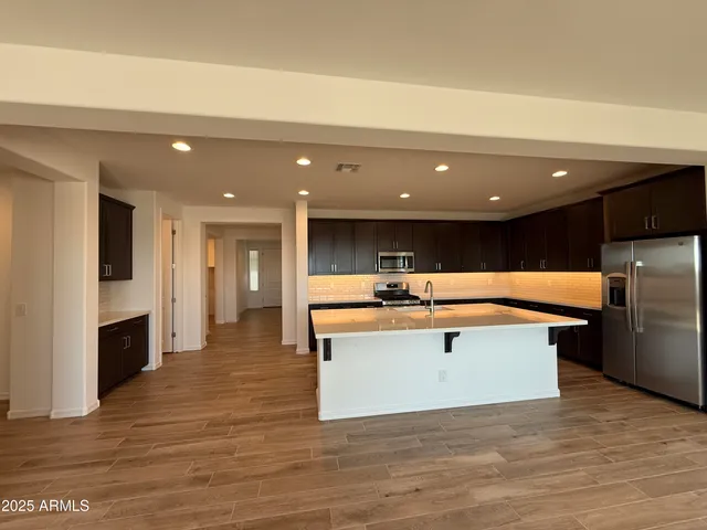 a view of kitchen with stainless steel appliances wooden floor and living room
