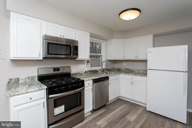 a kitchen with cabinets stainless steel appliances and wooden floor