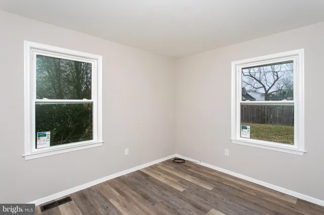 a view of a big room with wooden floor and windows