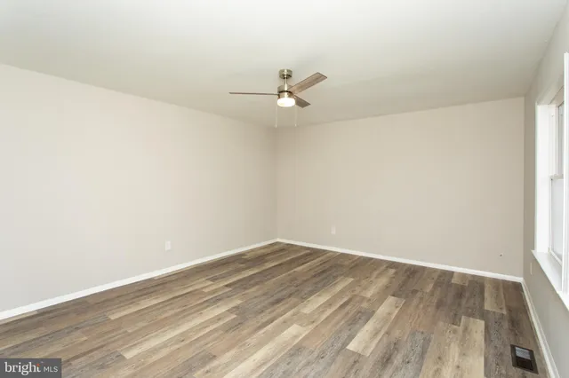 an empty room with wooden floor and fan