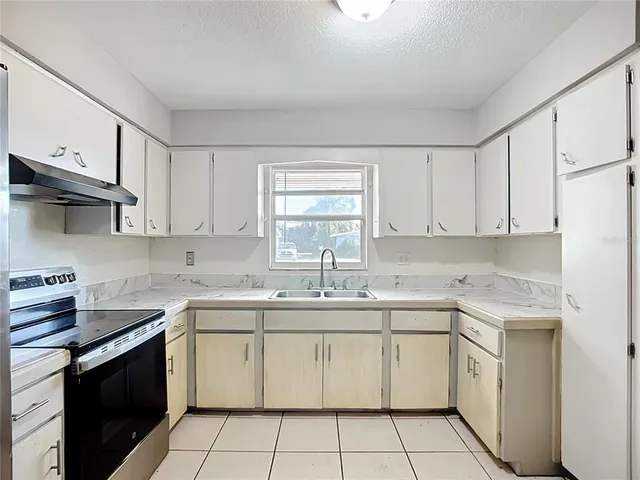 a kitchen with granite countertop a refrigerator and a stove top oven