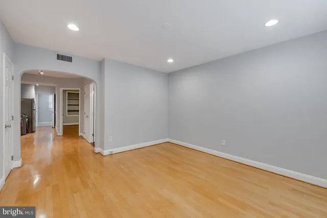 an empty room with wooden floor and natural light