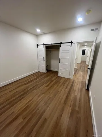 an empty room with wooden floor and entrance