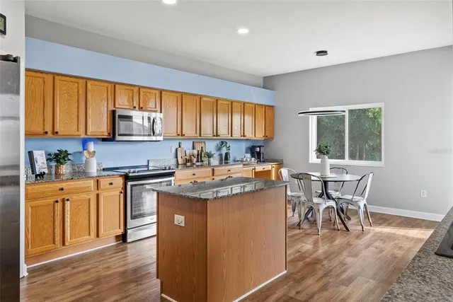 a kitchen with granite countertop wooden cabinets a counter top space appliances and a window