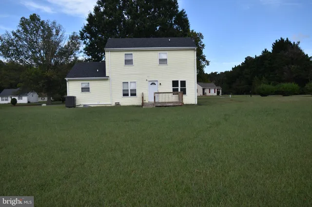 a view of a white house with a big yard and large trees