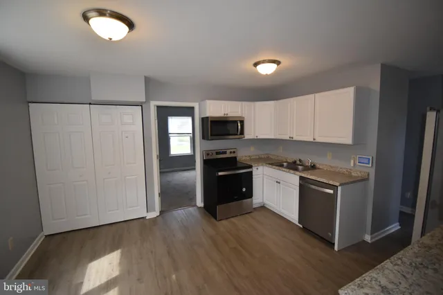 a kitchen with granite countertop a refrigerator and a stove top oven