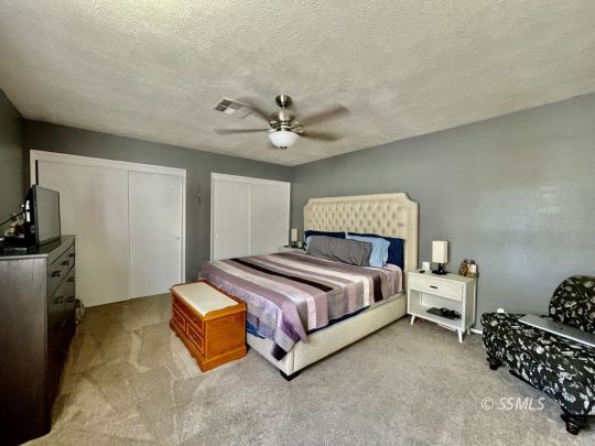 1009 West Iowa Avenue Ridgecrest, CA 93555 - Photo 10 of 26 a spacious bedroom with a bed and a ceiling fan