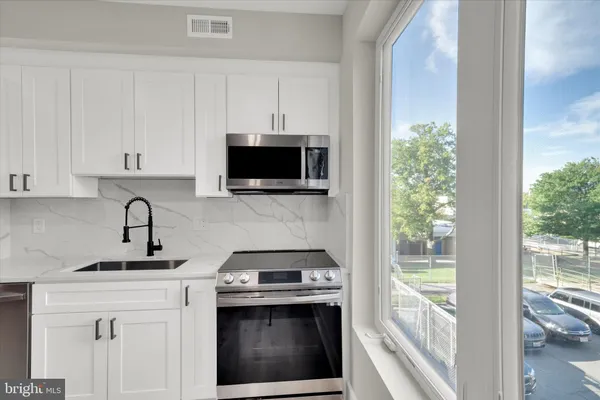 a kitchen with stainless steel appliances granite countertop a stove a sink and a microwave