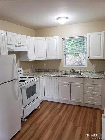 a kitchen with granite countertop white cabinets and white appliances