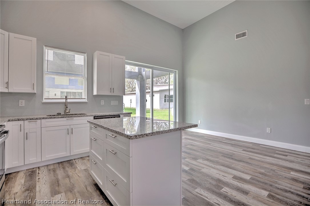 2545 Odessa Road Avon Park, FL 33825 - Photo 10 of 24 a kitchen with granite countertop white cabinets and wooden floor