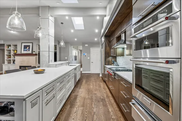 a large kitchen with stainless steel appliances a large counter top a stove and a chandelier