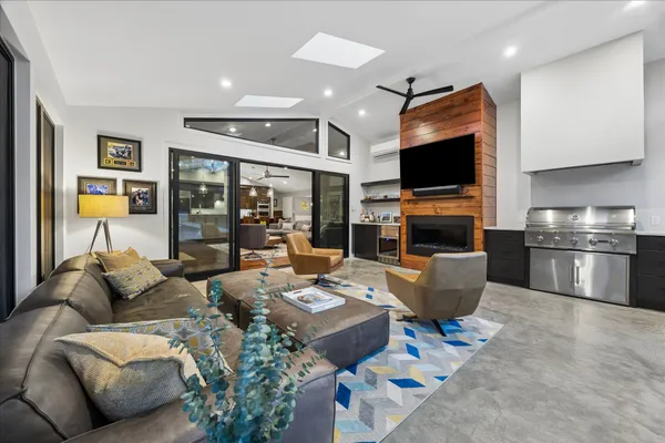 a living room with furniture floor to ceiling window hardwood floor and a flat screen tv