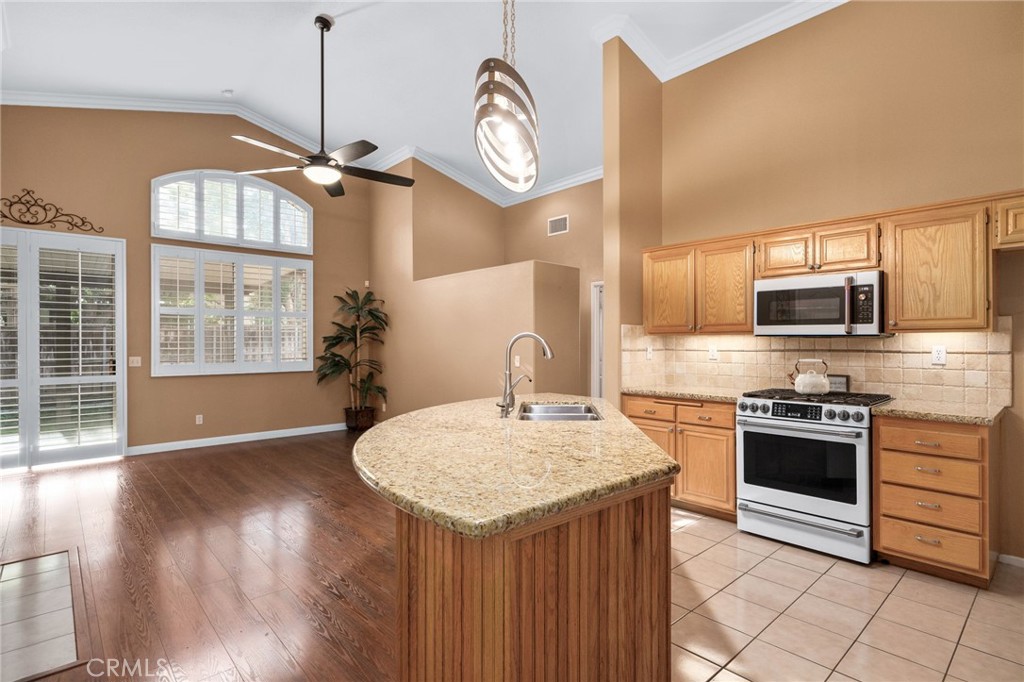 9403 Old Post Drive Rancho Cucamonga, CA 91730 - Photo 11 of 38 a kitchen with kitchen island granite countertop a stove a sink a center island and wooden floor
