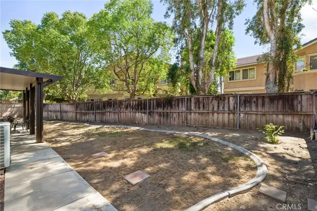 a view of a backyard with wooden fence and a large tree