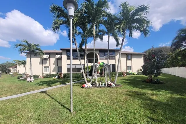 a view of a house with a yard and palm trees